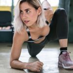Focused woman with blond hair stretching indoors, showcasing determination and fitness.